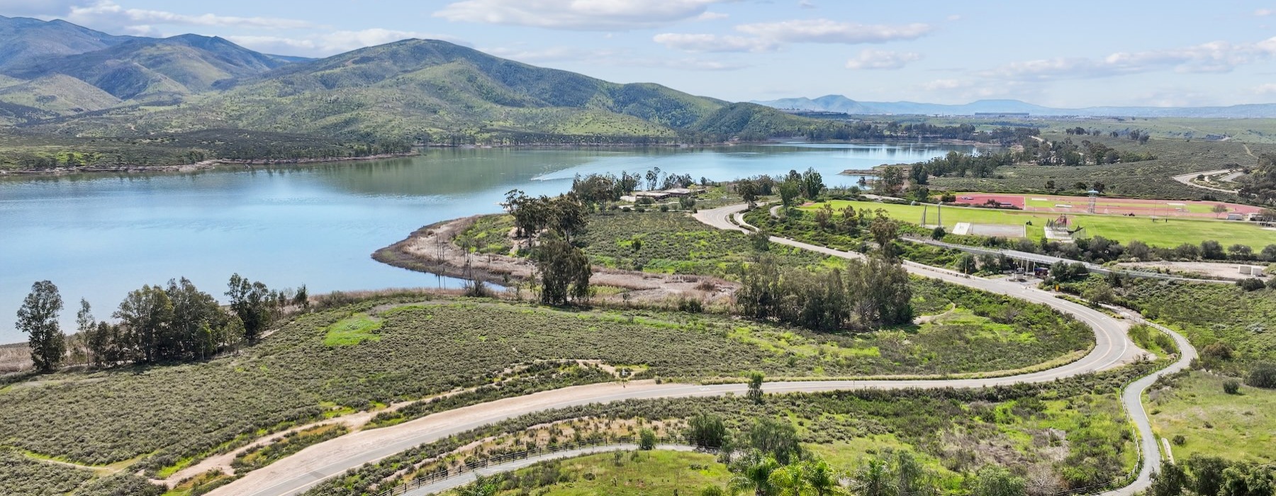 an aerial view of a landscape with water and a road